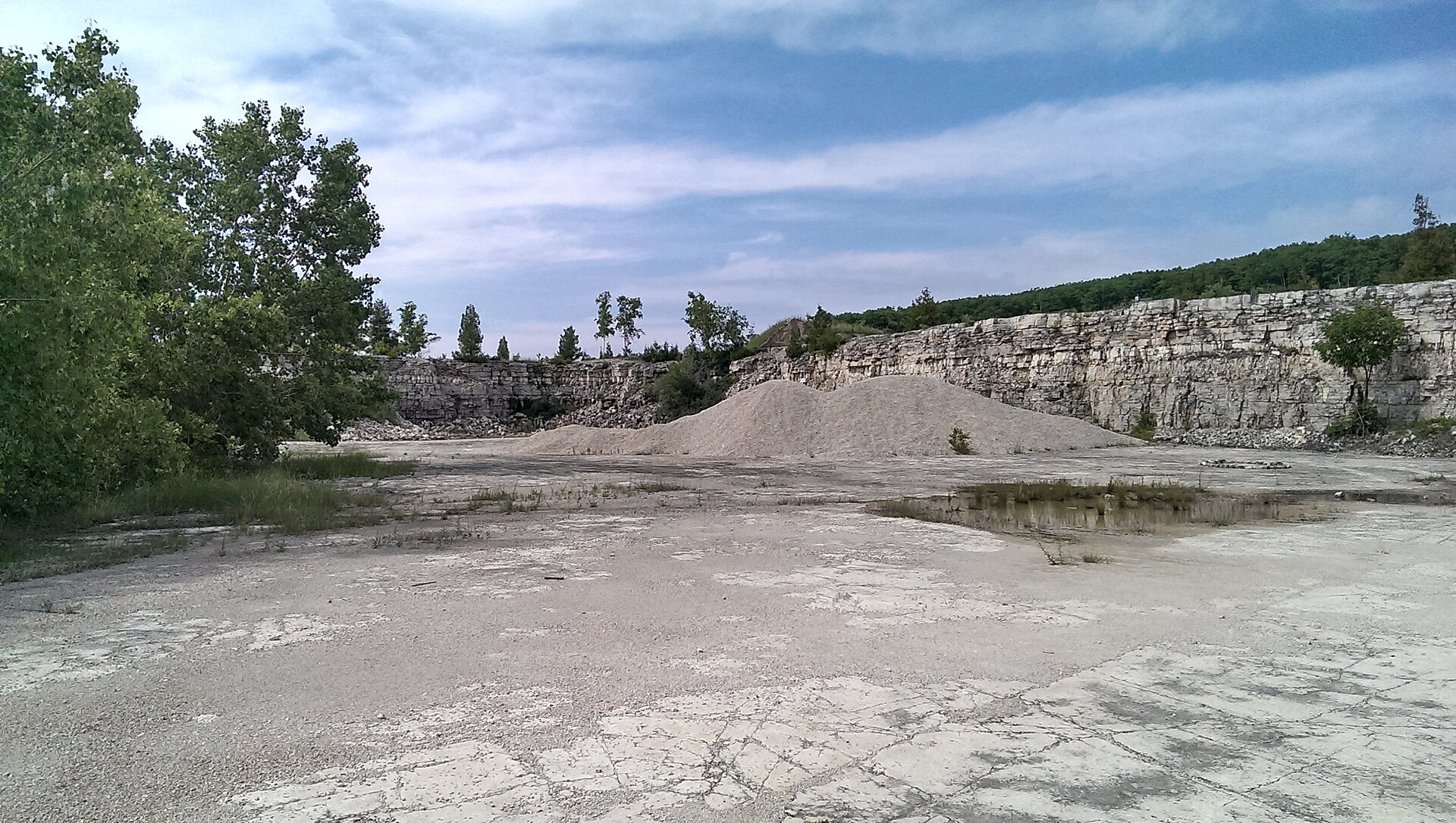Mound of crushed gravel and stone stockpiled by grade in an open quarry yard